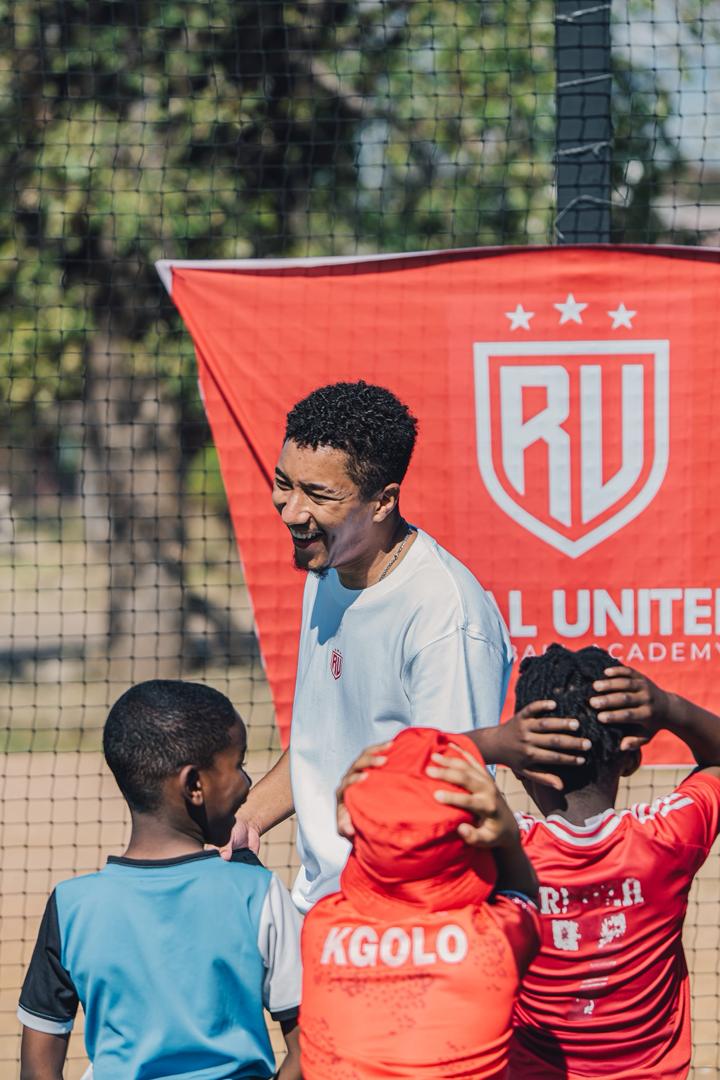 Real United coach connecting with young players beside the academy banner
