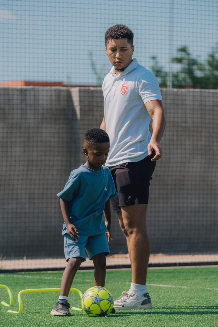 Real United coach helping a young player develop confidence on the ball